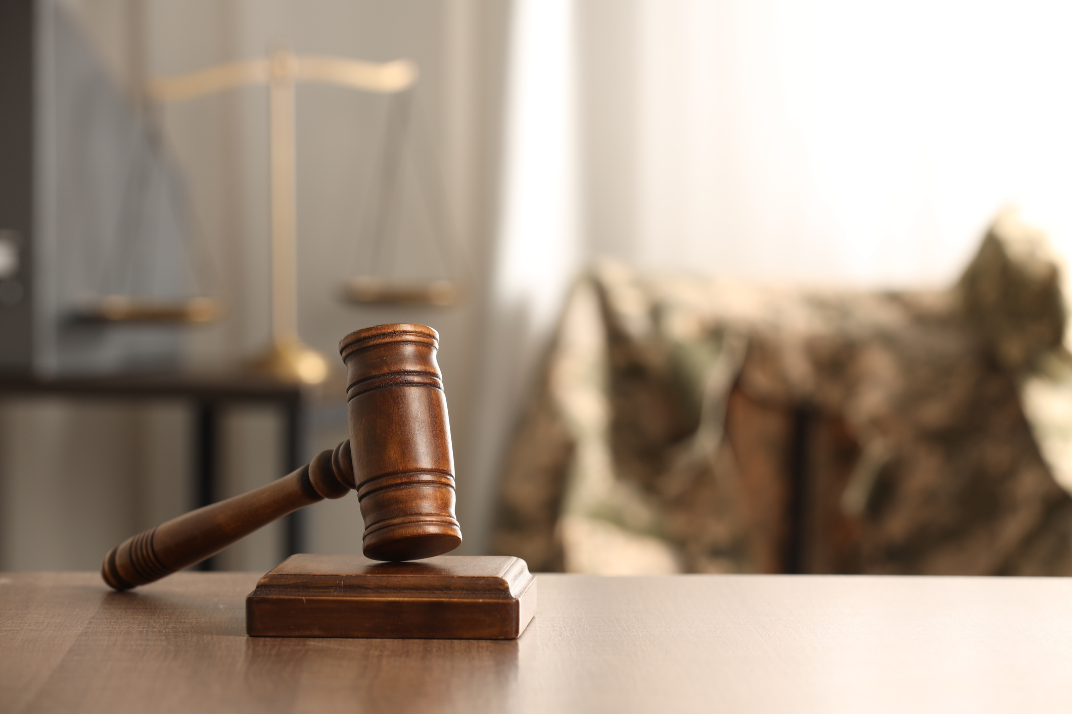 Gavel and scales with camouflage military uniform