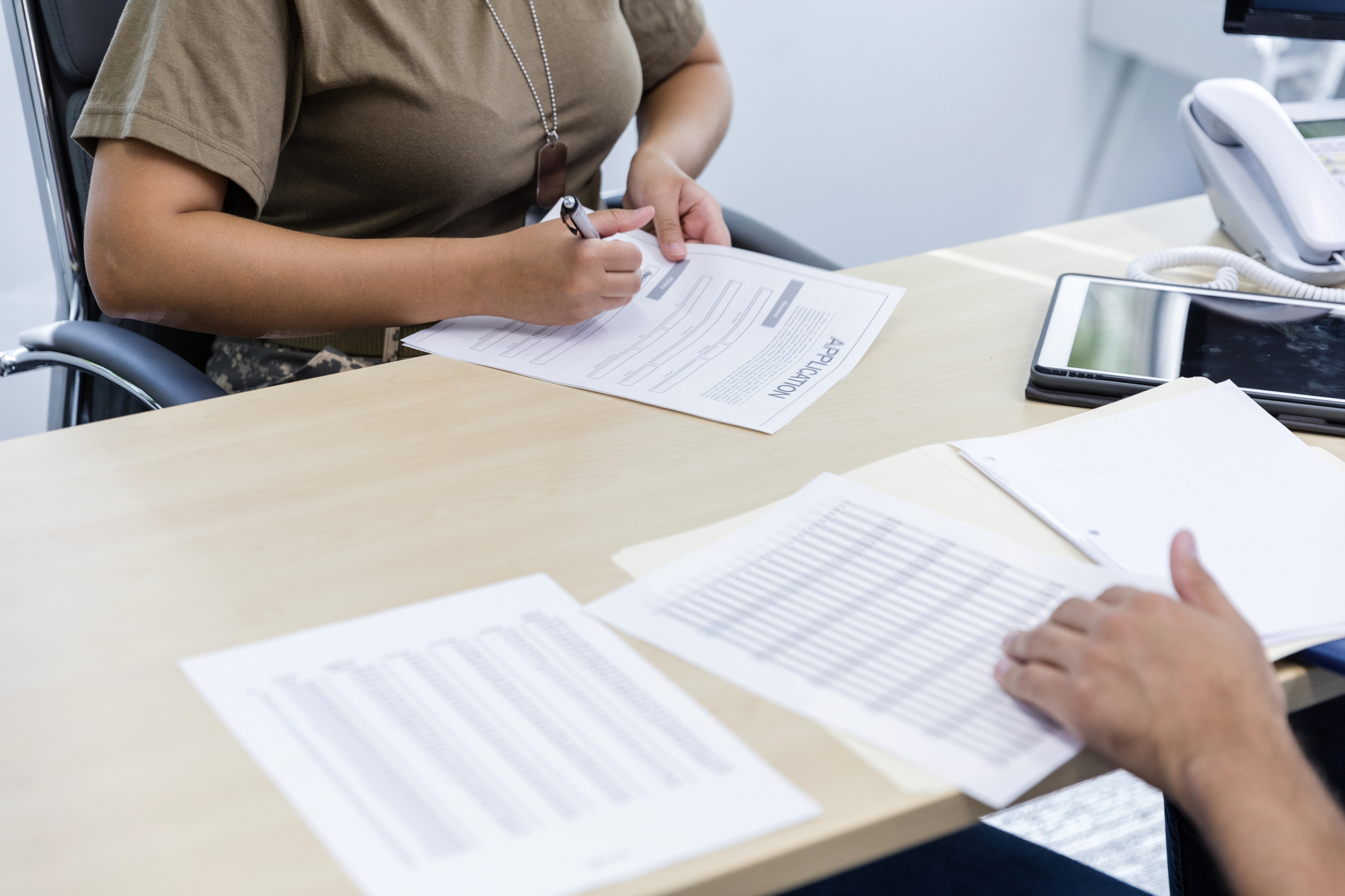 Person signing application form at office desk