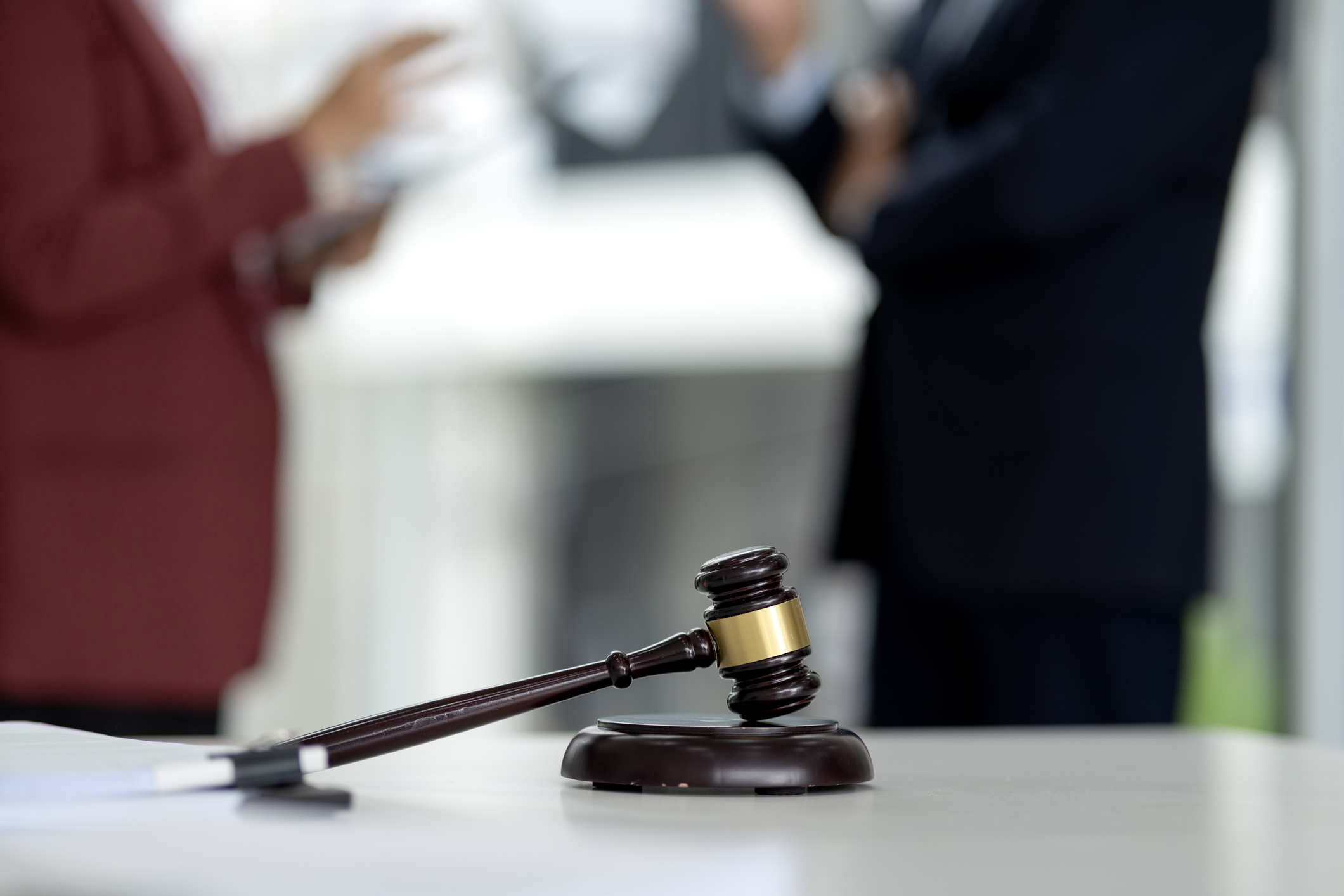 Gavel on table with blurred lawyers behind